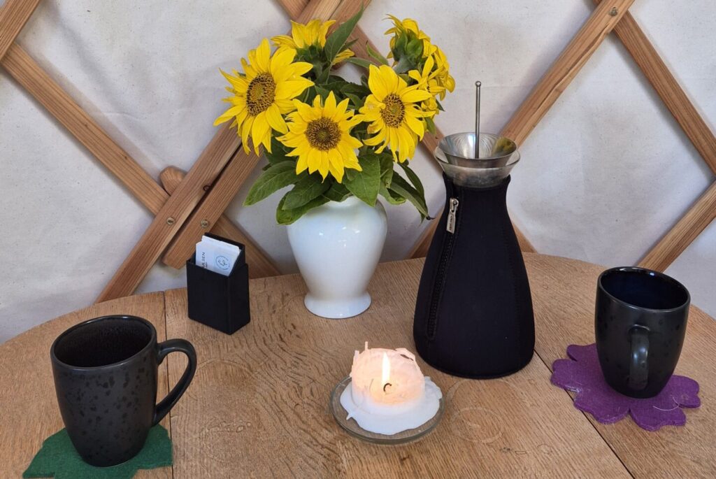 En kande te, to kopper, et stearin lys og en buket blomster står på bordet i jurten, klar til at dagens klient kommer til psykoterapi hos Pia Klit Poulsen MPF